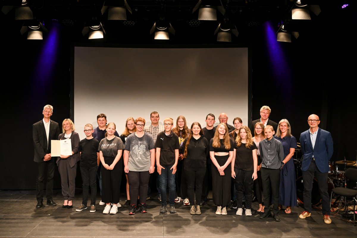 Die Schülerinnen und Schüler der Theater-AG bei der Überreichung der Urkunde durch Herrn Kultusminister Dr. Piazolo (links im Bild) an die Leiterin Frau Eva Kaiser (2. v. l.). rechts im Bild Herr Roland Börschel (Sonderschulrektor) und Frau Sonja König (Sonderschulkonrektorin, 2. v. r.), Roman Nowak (Leiter der Theater-Musik-AG, 3. v. r.) und Herr Schreiner (Technik, 5. v. r.)